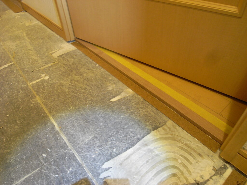 横浜市のマンションで廊下の直貼りフローリングの張り替え工事で床見切り材を設置しています。