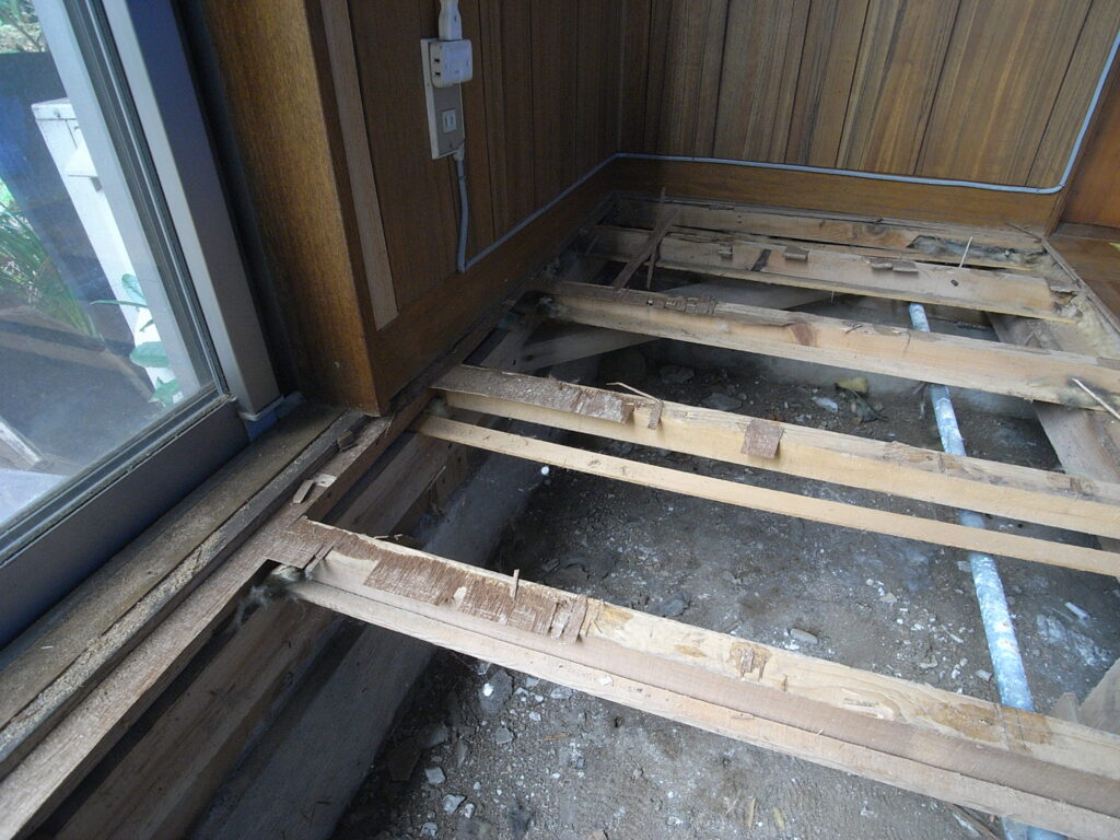 横浜市神奈川区の戸建てで床をはがした後の根太の上に接着剤と床の一部が残っています。