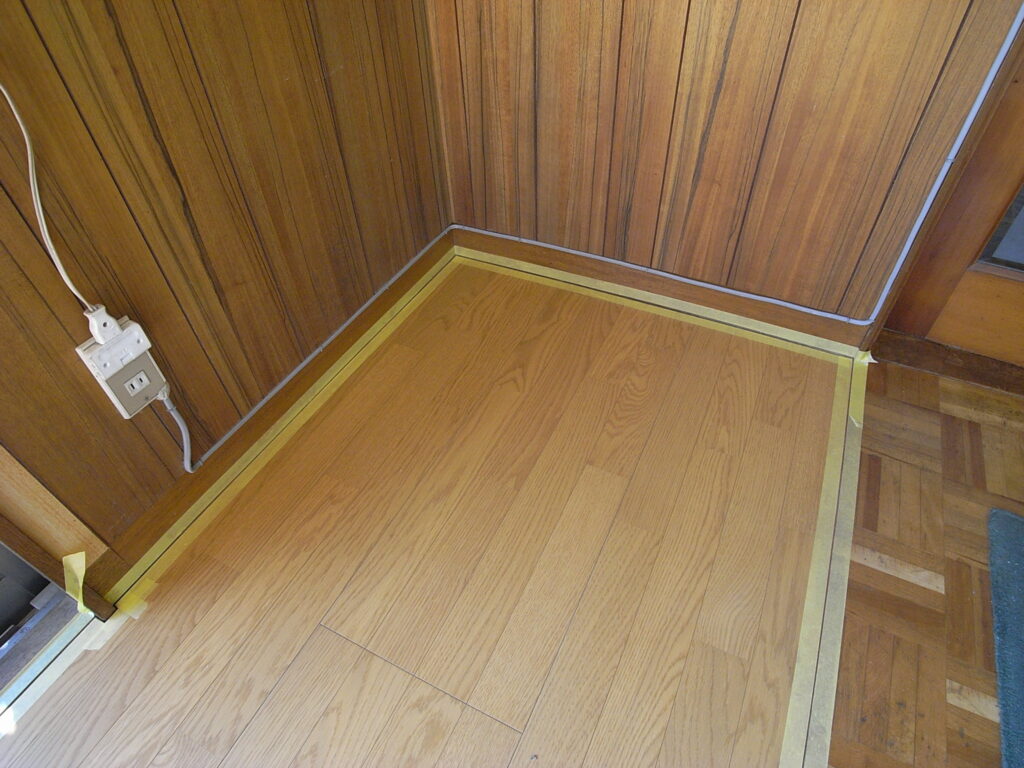 横浜市神奈川区の戸建てでフローリングの部分張替えが完了した後に、隙間を埋めるための養生として、マスキングテープを貼っています。