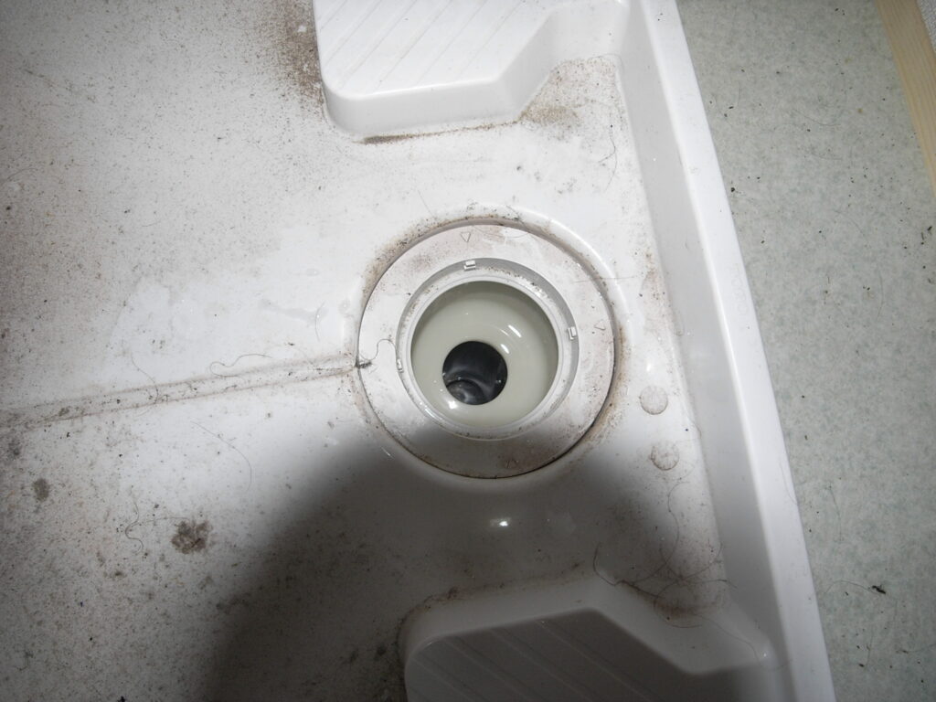 排水の流れが悪くなった防水パンの排水口部分。